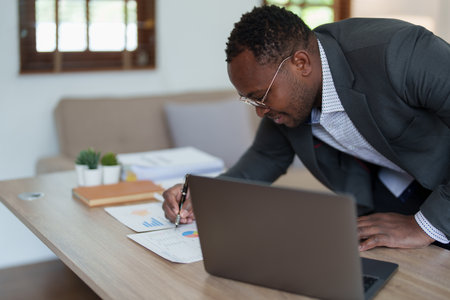 middle aged man American African using computer laptop with planning working on financial document, tax, exchange, accounting and Financial advisor. auditor or audit concepts.の写真素材