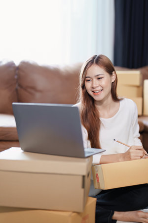 Starting small business entrepreneur of independent Asian female online seller packing products to...
