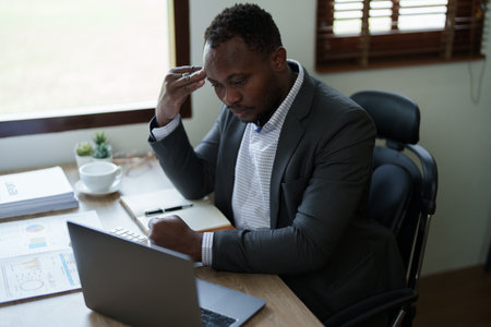 Burnout American African business man in stress works with many paperwork document, migraine attack, Freelance, work from home.の写真素材