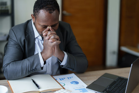 Burnout American African business man in stress works with many paperwork document, migraine attack, Freelance, work from home.の写真素材