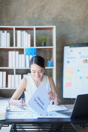 Portrait of a thoughtful Asian businesswoman looking at financial statements and making marketing plans using a computer on her desk.の写真素材