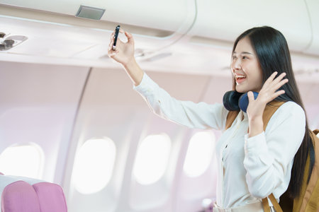 Asian business woman passenger sitting on business class luxury plane while working using smart phone mobile talking or video conference and travel concept.の写真素材