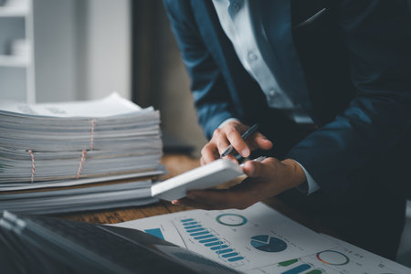 Young asian male work with financial papers at home count on calculator before paying taxes receipts online, planning budget glad to find chance for economy saving money, audit conceptsの写真素材