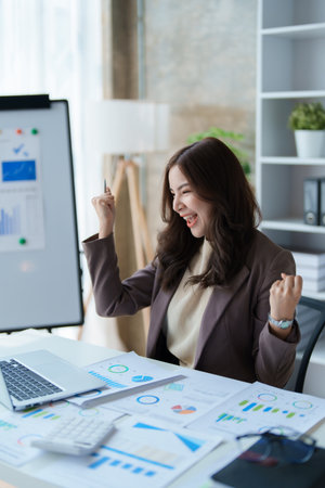 Beautiful young teen asian businesswomen using computer laptop with hands up in winner is gesture, Happy to be successful celebrating achievement success.の写真素材
