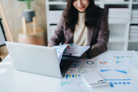 businesswoman or accountant working on calculator and laptop computer to calculate business data during using accountancy document at office.の写真素材