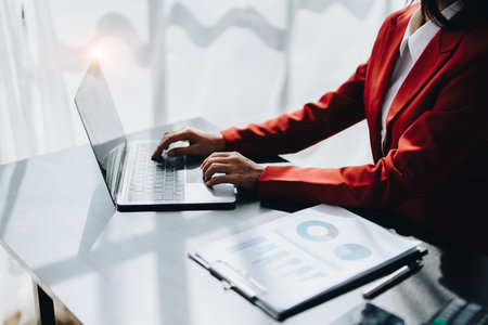 Beautiful young teen asian businesswoman using laptop computer and paperworks with planning working on financial document, tax, exchange, accounting and Financial advisor.の写真素材