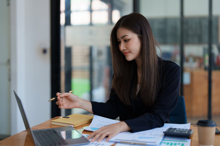 Beautiful young teen asian business woman meeting at on computer laptop with planning working on financial document, tax, exchange, accounting and Financial advisor. High quality photoの写真素材