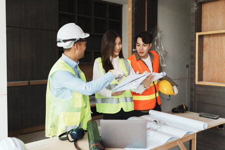 multi ethnic engineer brainstorming and measuring for cost estimating on paperworks and floor plan...