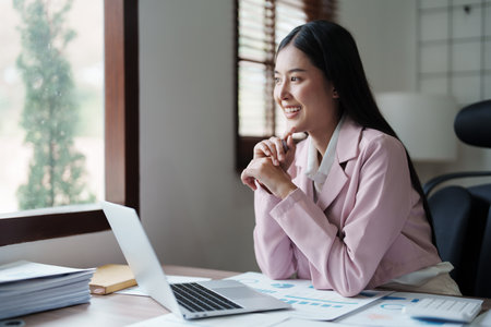 Portrait of a woman business owner showing a happy smiling face as he has successfully invested her business using computersの写真素材