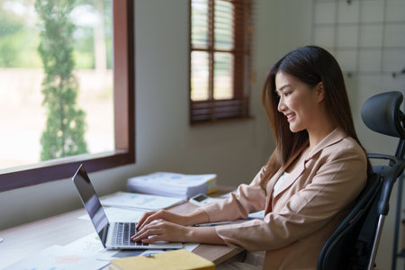 Young asian businesswoman manager, lawyer or company employee holding accounting bookkeeping documents checking financial data or marketing report working in office with laptop. Paperwork management.の写真素材