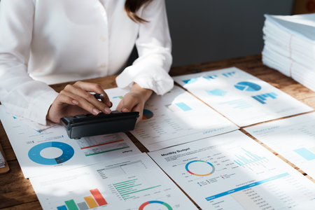 Young asian female work with financial papers at home count on calculator before paying taxes receipts online, planning budget glad to find chance for economy saving money, audit concepts.の写真素材