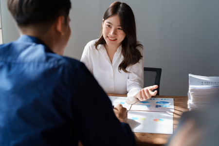 Accountant checking financial statement or counting by calculator income for tax form, Business woman sitting and working with colleague discussing the desk in office. Audit concept.の写真素材