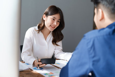 Accountant checking financial statement or counting by calculator income for tax form, Business woman sitting and working with colleague discussing the desk in office. Audit concept.の写真素材