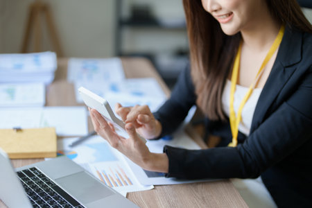 businesswoman or accountant working on calculator and laptop computer to calculate business data during using accountancy document at office.の写真素材