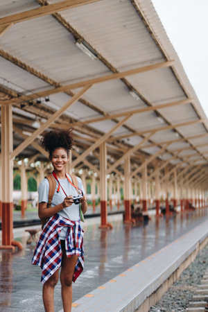 Asian teenage girl african american traveling using a camera take a photo to capture memories while waiting for a train at the stationの写真素材