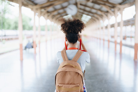 Asian teenage girl african american traveling using a camera take a photo to capture memories while waiting for a train at the stationの写真素材