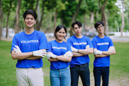 Volunteers of various nationalities are showing solidarity, donating their personal time, holding black trash bags to collect plastic waste for recycling to reduce pollution in a public parkの写真素材