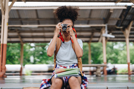 Asian teenage girl african american traveling using a camera take a photo to capture memories while waiting for a train at the stationの写真素材