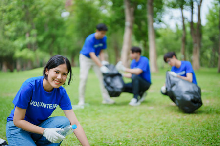 Multiethnic volunteers donate their time holding black garbage bags to collect plastic waste for recycling to reduce pollution in a public parkの写真素材
