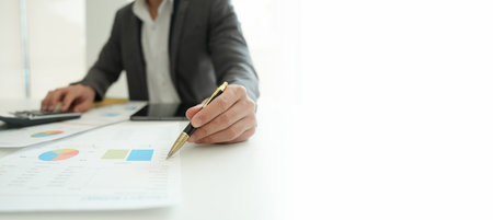 businessman or accountant working on calculator and laptop computer to calculate business data during using accountancy document at officeの写真素材