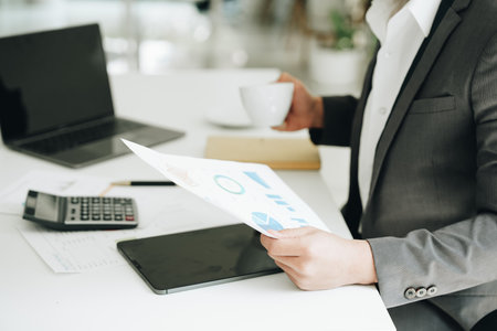 Young asian male work with financial papers at home count on calculator before paying taxes receipts online, planning budget glad to find chance for economy saving money, audit conceptsの写真素材