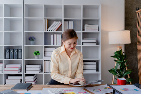 businesswoman in a black suit inside the office using tablet computer, audit paperwork for customers to contact, business people conceptの写真素材