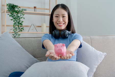 Asian young woman holding a piggy bank and coin, Savings conceptsの写真素材