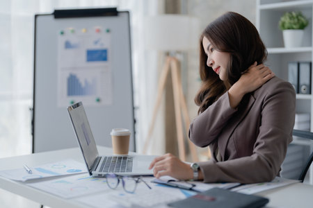 Portrait of a young Asian woman suffering from acute headache and occipital pain from sitting for a long time at workの写真素材