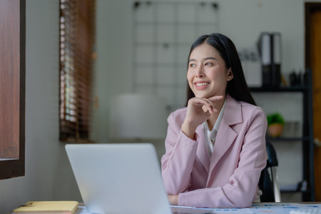 Excited businesswoman using computer laptop while in office, business conceptsの写真素材