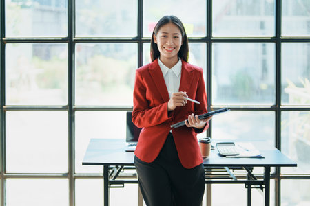 Young businesswoman professional business woman executive, female company or manager holding digital tablet using pad technology device working standing in modern corporate officeの写真素材