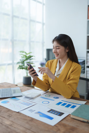 Consultant, advisor, Asian business woman working on the computer and using smartphone mobile talking work financial and marketing business planning company profits, marketing planning budgetの写真素材