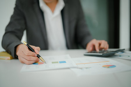 Young asian male work with financial papers at home count on calculator before paying taxes receipts online, planning budget glad to find chance for economy saving money, audit conceptsの写真素材