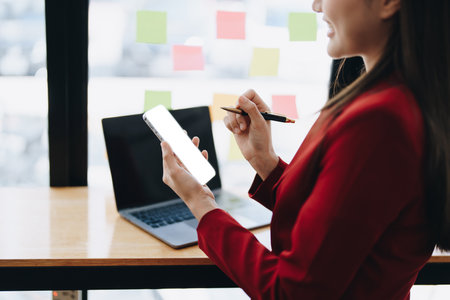 Consultant, advisor, Asian business woman working on the computer and using smartphone mobile talking work financial and marketing business planning company profits, marketing planning budgetの写真素材