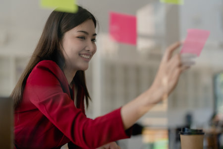 Beautiful young teen asian businesswoman using note pad thinking with planning working on financial...