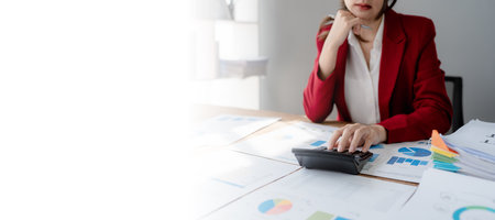 Beautiful young teen asian businesswoman using computer laptop and calculator for calculate with planning working on financial document, tax, exchange, accounting and Financial advisor.の写真素材