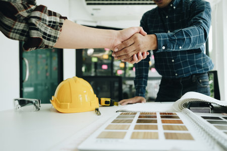 Engineers, designers and interior designers are handshake shack hands deal finalizing the design of interiors by discussing selecting materials and colors to design rooms to present to clientsの写真素材