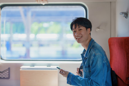 Asian teenage male traveler using her smart phone mobile while waiting for a train at a station