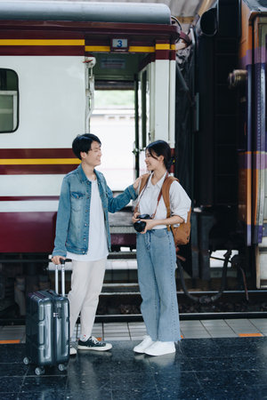 Tourist couples showing their love and happiness in a sweet way while waiting for their journey at the train stationの写真素材