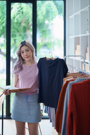 Beautiful Asian woman, blogger, blog, presenting fashion clothes, live video, social media, record her, sell online via digital cameras, sme or small business ecommerce concepts.の写真素材