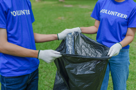 Multiethnic volunteers donate their time holding black garbage bags to collect plastic waste for recycling to reduce pollution in a public parkの写真素材
