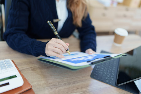 Portrait of a thoughtful Asian businesswoman looking at financial statements and making marketing plans using a computer on her desk.の写真素材
