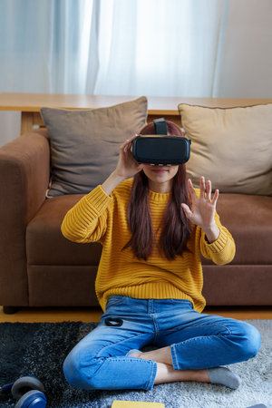 portrait of a young Asian woman using virtual reality simulator headset at home.の写真素材