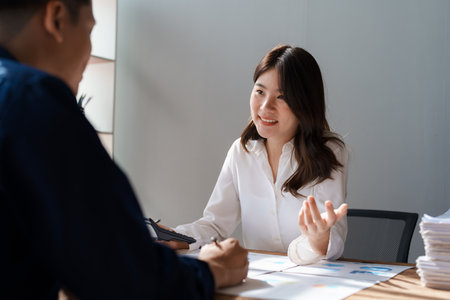Accountant checking financial statement or counting by calculator income for tax form, Business woman sitting and working with colleague discussing the desk in office. Audit concept.の写真素材
