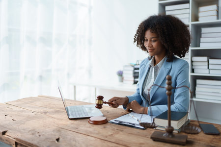 Young african american lawyer studying case for client and holding gavel in a symbolic gesture against her opponent in court Legal and lawyer conceptsの写真素材