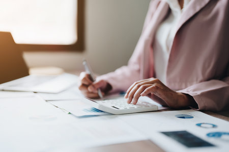 businesswoman or accountant working on calculator and laptop computer to calculate business data during using accountancy document at office.の写真素材