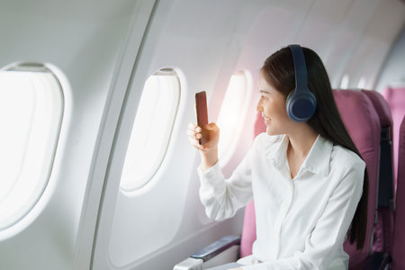 Young Asian attractive business woman passenger sitting on business class luxury plane while wearing...