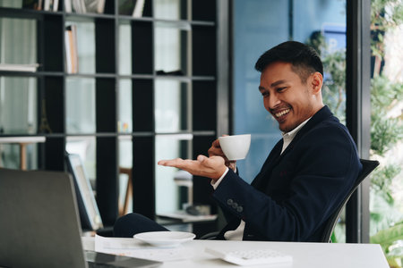 Portrait of a business man talking on the computer and drinking coffeeの写真素材