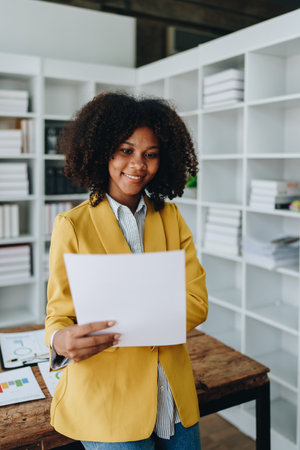 Beautiful young African american businesswoman using laptop computer and paperworks with planning working on financial document, tax, exchange, accounting and Financial advisor.の写真素材