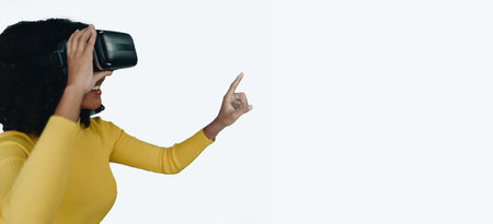 Positive African American woman teenager in futuristic VR helmet laughing and relaxing. Youthful...