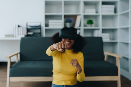 Positive African American woman teenager in futuristic VR helmet laughing and relaxing. Youthful...